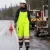 Woman roadside worker wearing ANSI Class E waterproof reflective safety bibs in wet weather work condition