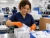 Female worker wearing 7 mil orange nitrile disposable gloves while packing medical devices in a clean production facility