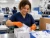 Female worker wearing 7 mil orange nitrile disposable gloves while packing medical devices in a clean production facility