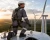 Renewable energy worker wearing a gray FR coverall and back-attached fall protection harness on top of a wind turbine.