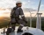 Renewable energy worker wearing a gray FR coverall and back-attached fall protection harness on top of a wind turbine.