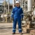 Worker wearing a blue FR coverall flame resistant work suit at an oil, gas, and petrochemical facility