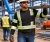 Construction worker wearing a black reflective long sleeve safety shirt while carrying lumber on a jobsite