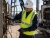 Oilfield electrical worker wearing a CAT 2 FR hi-vis vest while inspecting equipment wiring