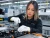 Female EV factory worker wearing white knit gloves while assembling electric vehicle battery components