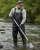 Environmental worker wearing black waterproof waders while collecting river water samples