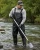 Environmental worker wearing black waterproof waders while collecting river water samples