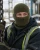 Worker wearing an olive green knit balaclava while handling equipment in cold outdoor conditions