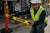 Worker applying yellow caution tape around a restricted industrial work area