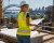 Female architect wearing a yellow hi-vis safety vest while reviewing blueprints on a construction site.