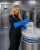 Female lab worker wearing blue shoulder-length cryogenic gloves while handling samples in a cryogenic storage lab.