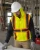Construction worker wearing an ANSI Class 2 yellow hooded hi-vis safety vest while reviewing plans at a jobsite