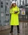 Female utility worker wearing a high-visibility yellow arc flash raincoat while inspecting electrical equipment in a wet power substation environment.