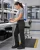 Women’s black anti-static cargo work pants worn by a technician working at an electronics assembly bench in a clean manufacturing environment.