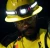 Industrial worker wearing a yellow hard hat with headlamp, safety glasses, and hi-vis workwear in a low-light work environment.