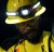 Industrial worker wearing a yellow hard hat with headlamp, safety glasses, and hi-vis workwear in a low-light work environment.