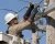 Utility lineman wearing Class 4 electrical insulating rubber gloves while working on high-voltage overhead power line equipment from a bucket truck.