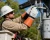 Utility lineman wearing goat leather electrical glove protectors while servicing overhead power distribution equipment from a bucket truck.