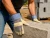 Worker wearing leather palm safety cuff gloves while lifting concrete blocks on construction site