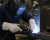 Welder wearing white leather welding gloves while welding steel in an industrial fabrication shop