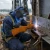 Welder wearing brown leather welding gloves while repairing steel bridge structure