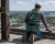 Worker wearing green fall protection harness with shock-absorbing lanyard attached to steel anchor