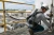 Worker using shock-absorbing safety lanyard attached to guardrail anchor on elevated industrial platform