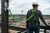 Worker using green shock-absorbing safety lanyard attached to steel anchor on construction site
