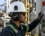 Worker wearing V3 cap-mounted passive ear muffs attached to a hard hat while operating equipment in an industrial plant environment