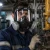 Worker wearing a North full-face air-purifying respirator with side-mounted cartridges while working in an industrial plant environment.