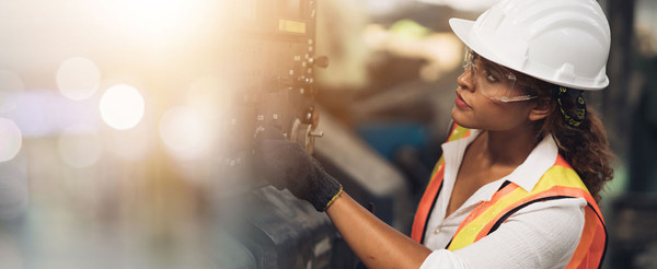 Woman wearing high-visibility workwear, safety glasses, and a hard hat