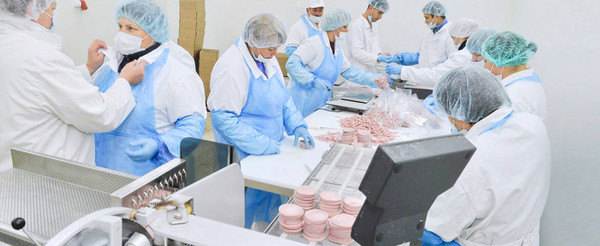 Food-production workers wearing disposable protective clothing and head coverings