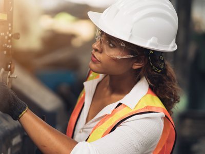 Woman wearing high-visibility workwear, safety glasses, and a hard hat