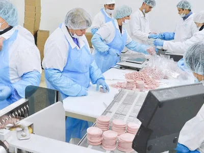 Food-production workers wearing disposable protective clothing and head coverings