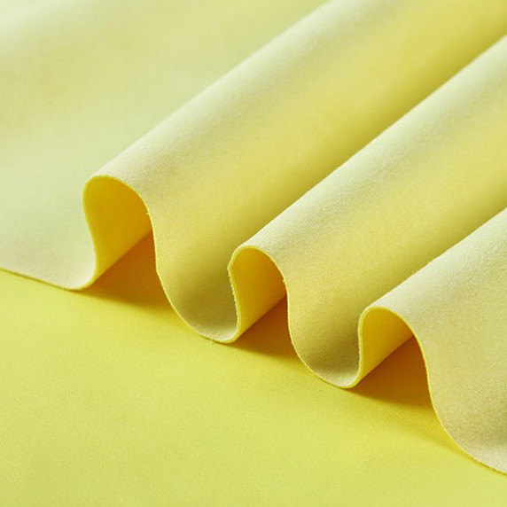 Gros plan sur la texture douce et l'élasticité du tissu suedette adhésif pour auto et DIY