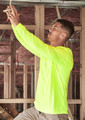 A man wearing a high visibility long sleeve tee in fluorescent yellow, working on electrical wiring in a construction setting.