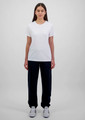 A woman stands wearing a white t-shirt and navy blue track pants, showcasing a simple, casual outfit.