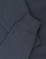A close-up of a navy oversized hoodie featuring ribbed cuffs and soft fleece material. It includes a logo.