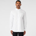 A white button-up Oxford shirt on a model, featuring a chest pocket and long sleeves. The shirt has a logo.