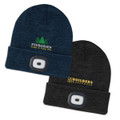 A navy beanie with a headlamp and logo, alongside a black beanie with a headlamp and another logo.