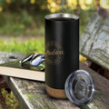 A drink bottle in black with a cork base and a clear lid, placed on a wooden surface with sunglasses and a book.