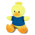 A yellow duck plush toy with an orange beak and feet, wearing a blue shirt, features a fluffy tuft on its head.