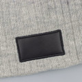 A grey cable knit beanie featuring a black patch, made from soft wool blend material.