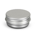 A silver lip balm tin with a smooth, rounded top and a ribbed edge. It has a minimalist design and a logo.