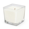 A square glass candle holder containing a white scented candle with a single wick.