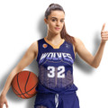 A woman in a navy blue basketball jersey with a cityscape design, holding a basketball and giving a thumbs up.