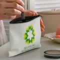 A small white cosmetic bag with a floral design and a zipper, being filled with a lipstick tube.