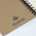 A spiral notebook with brown sugarcane paper cover, featuring lined pages and a logo on the front.