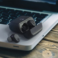 A pair of black Skullcandy Mod TWS earbuds and their charging case on a laptop keyboard.