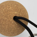 A round cork floating key ring with a black braided cord attached.